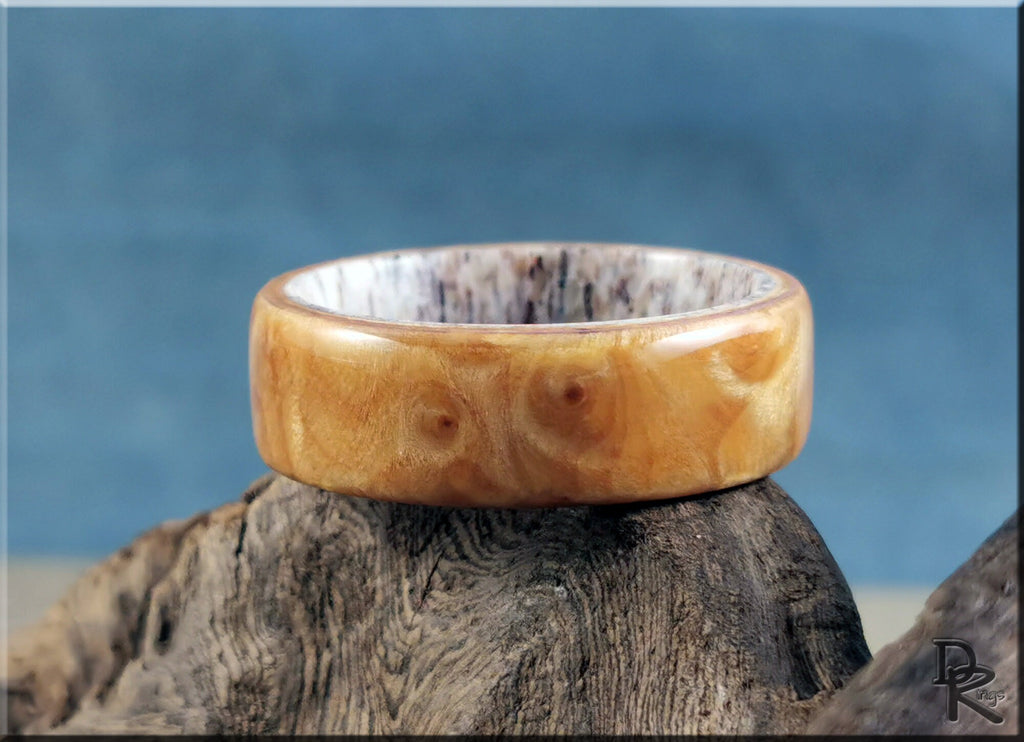 Wood ring on antler core by DR Rings displayed on rustic wood with blue background