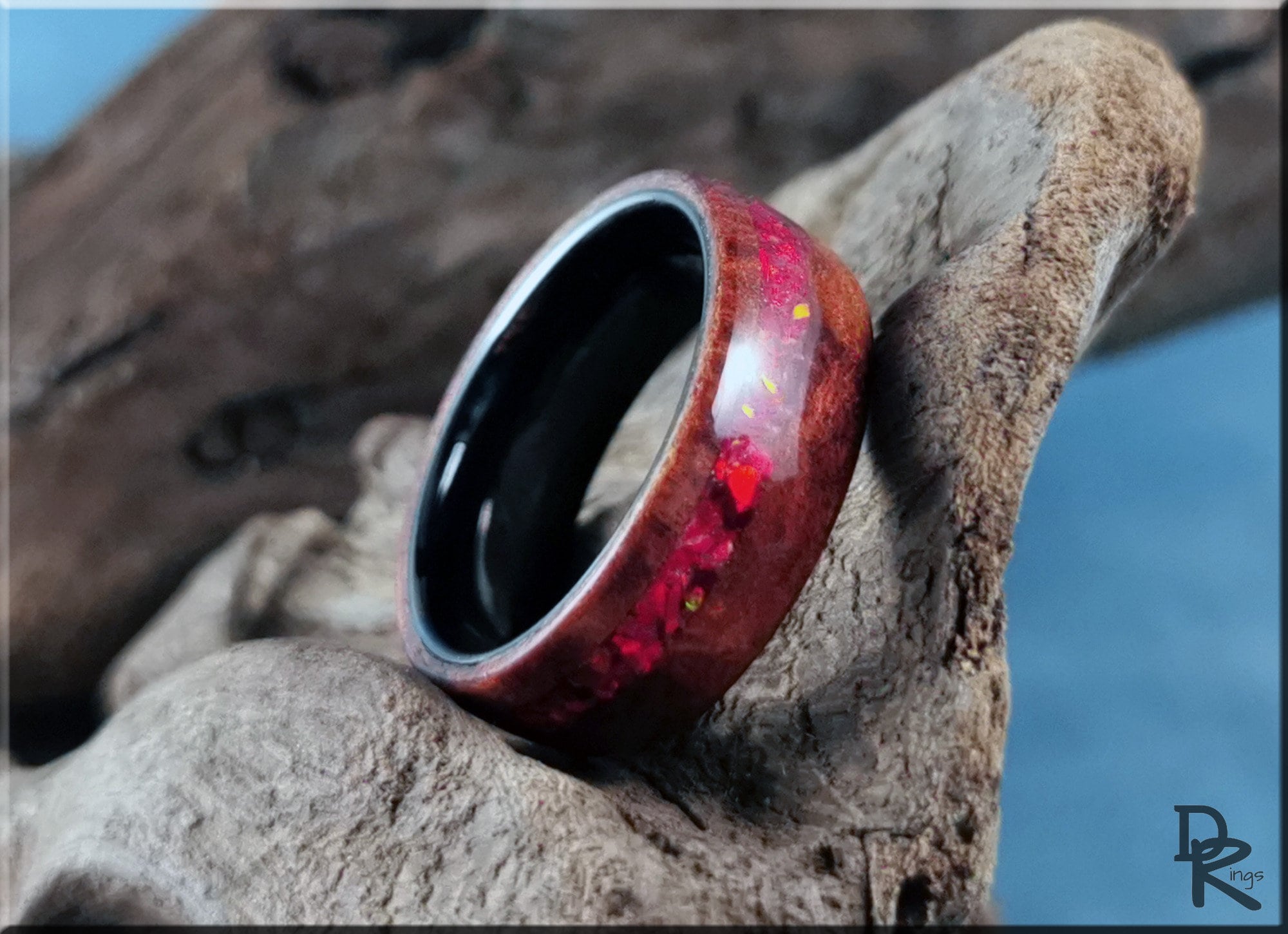 Wood ring with opal inlay featuring red iridescent stones set in a dark wood band by DR Rings