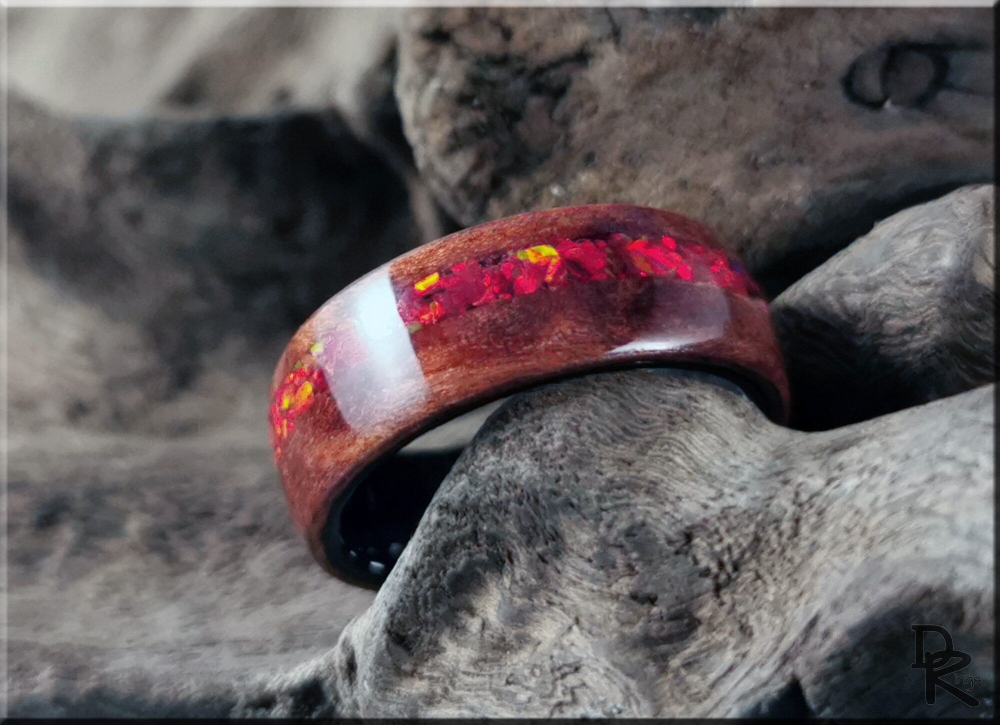 Wood ring with opal inlay featuring vibrant red and orange colors by DR Rings on rustic wood background