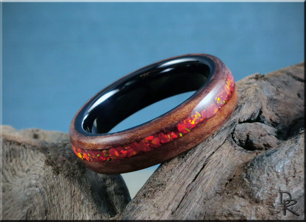 DR Rings wood ring with opal inlay featuring red opal accents and dark inner band on rustic wood