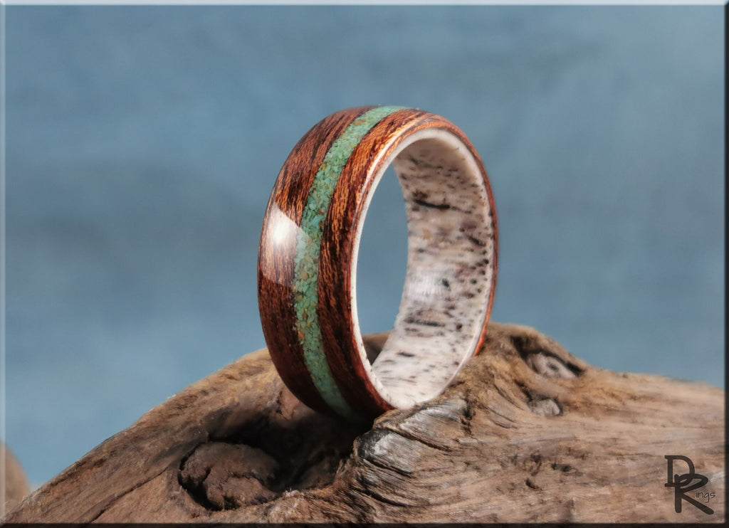 DR Rings wood ring with turquoise and antler inlay resting on a textured wooden surface