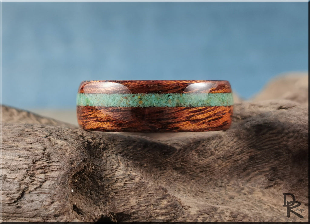 Wood ring with turquoise and antler inlay by DR Rings displayed on textured surface