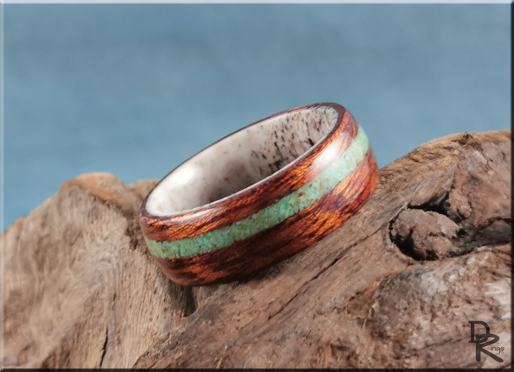 Wood ring with turquoise and antler inlay displayed on rustic wooden surface by DR Rings
