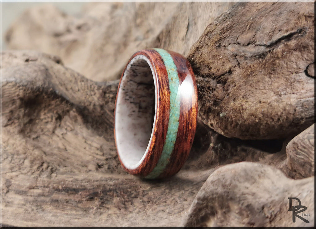 DR Rings wood ring with turquoise and antler inlay resting on natural wood background