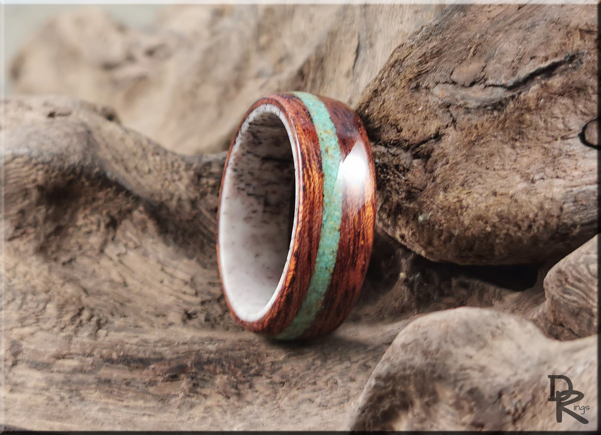DR Rings wood ring with turquoise and antler inlay resting on natural wood background